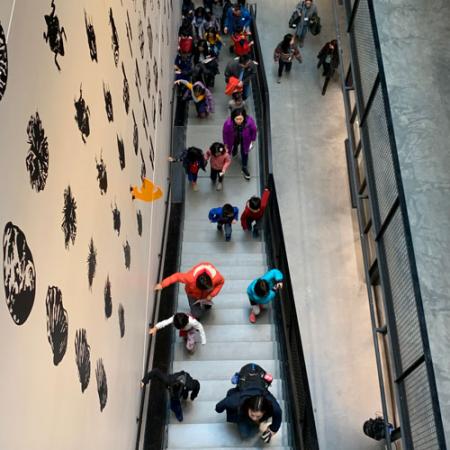 a group of children run up the stairs inside the new burke museum