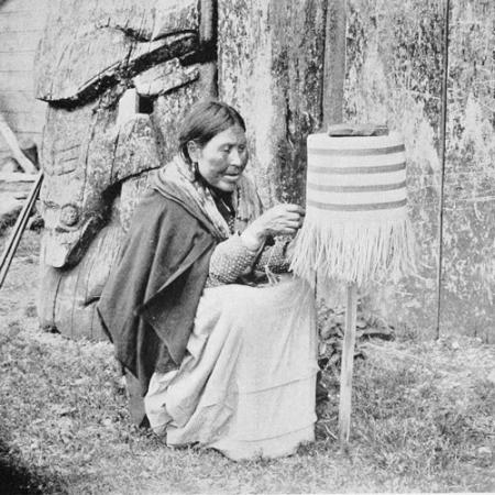 a woman sits and weaves a basket on a post
