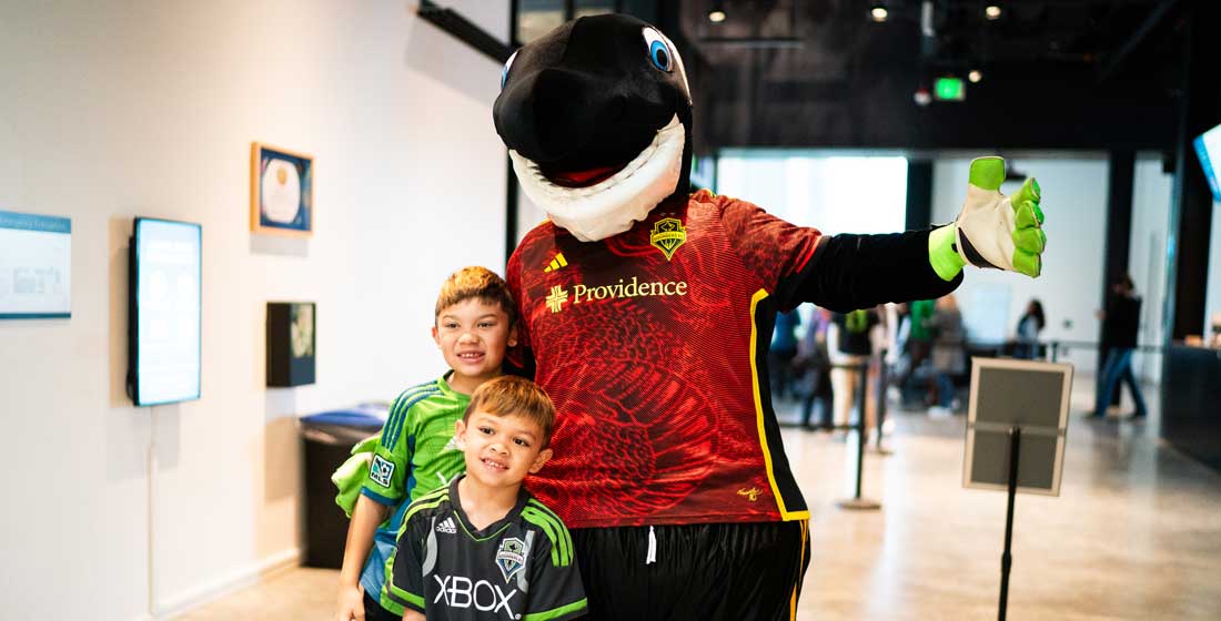 kids pose with sammy the sounder at sounders fc day at the burke museum