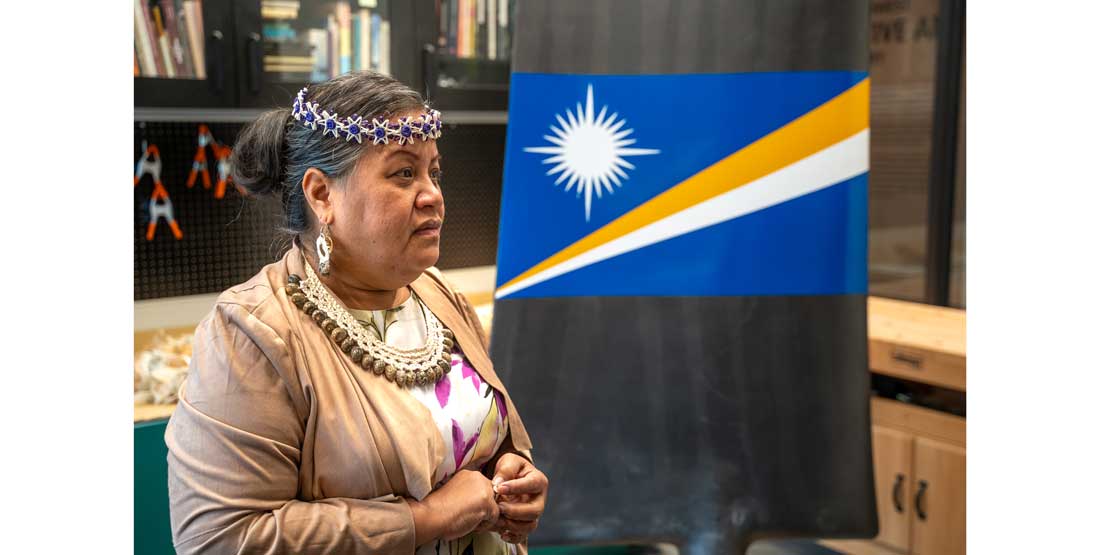 Marshallese master weaver Emma Joran stands next to the nuclear fan blade she created in collaboration with Blades of Change during a visit to the Burke in March 2024.